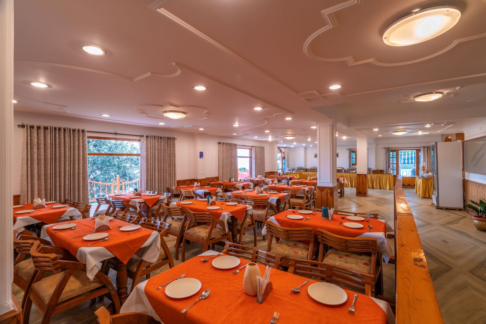 Een ruime eetzolder met meerdere tafels, stoelen en een buffetopstelling.