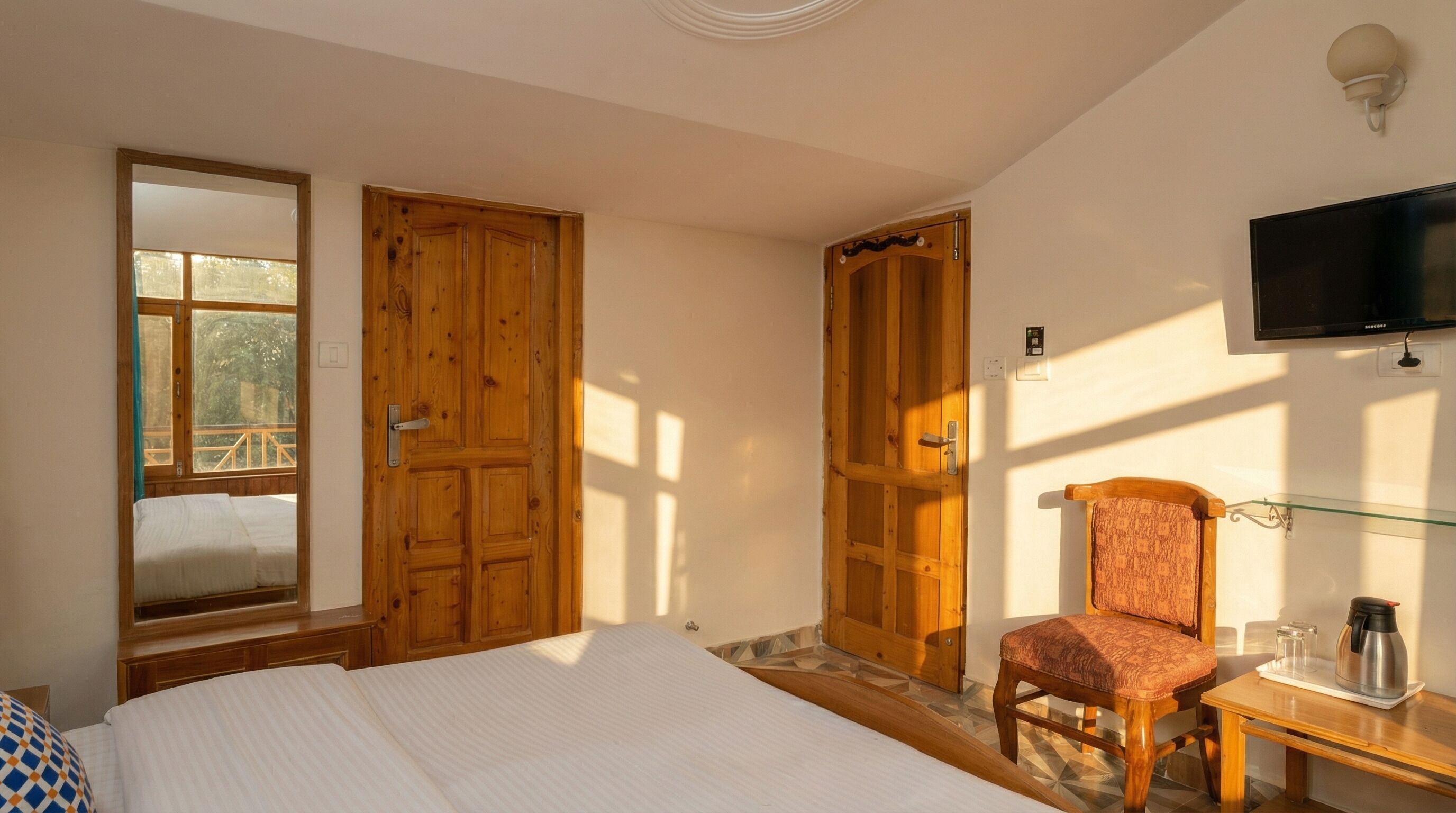 A bedroom with a bed, a chair, a TV, and wooden doors.