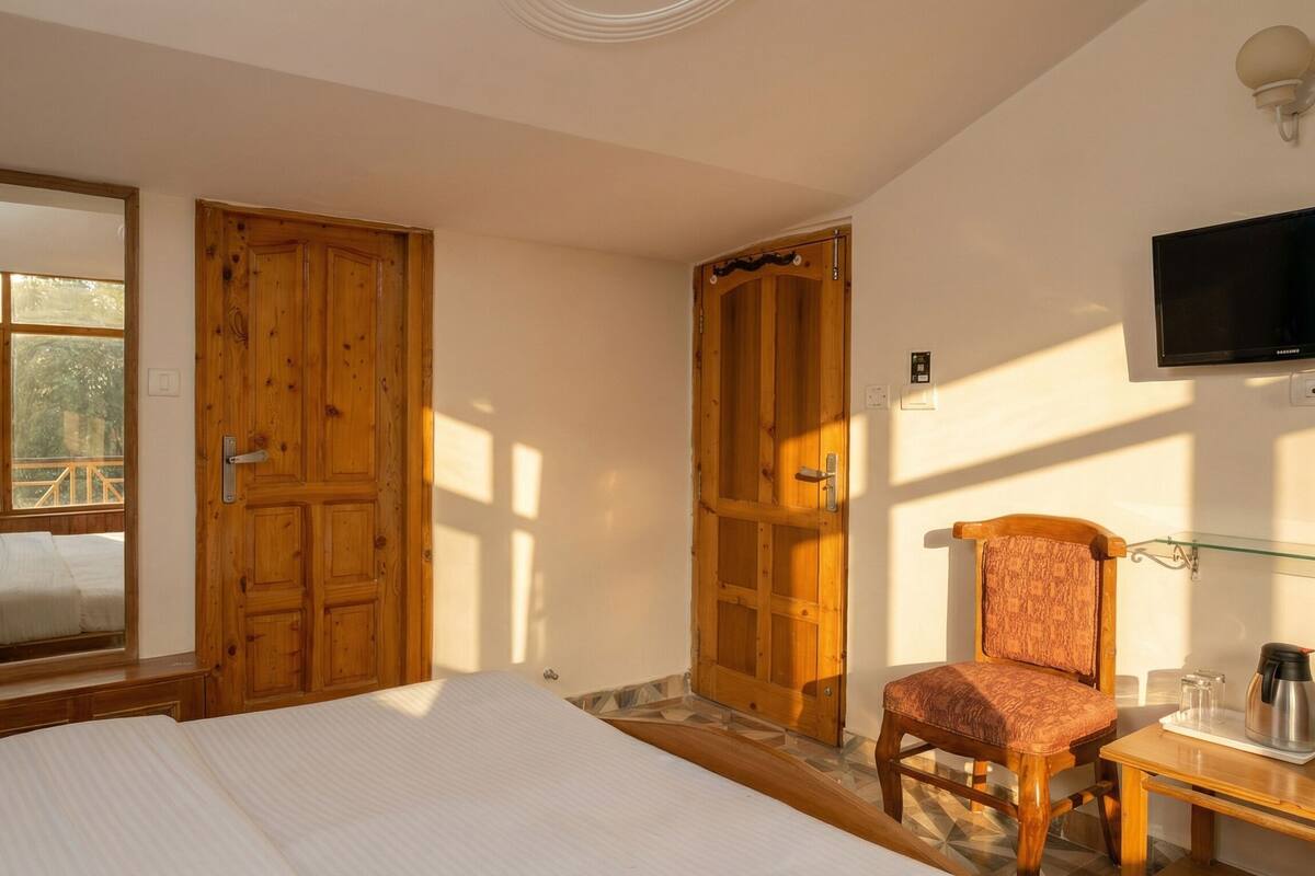 A bedroom with a bed, a chair, a TV, and wooden doors.