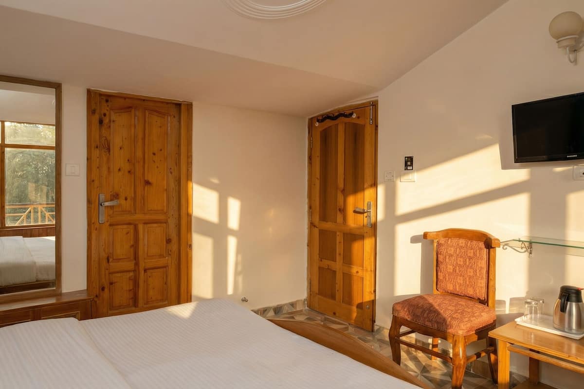 Un dormitorio con cama, una silla, un televisor y puertas de madera.