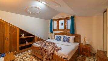Un dormitorio con una cama de madera, una mesita de noche, un armario y una ventana con cortinas.