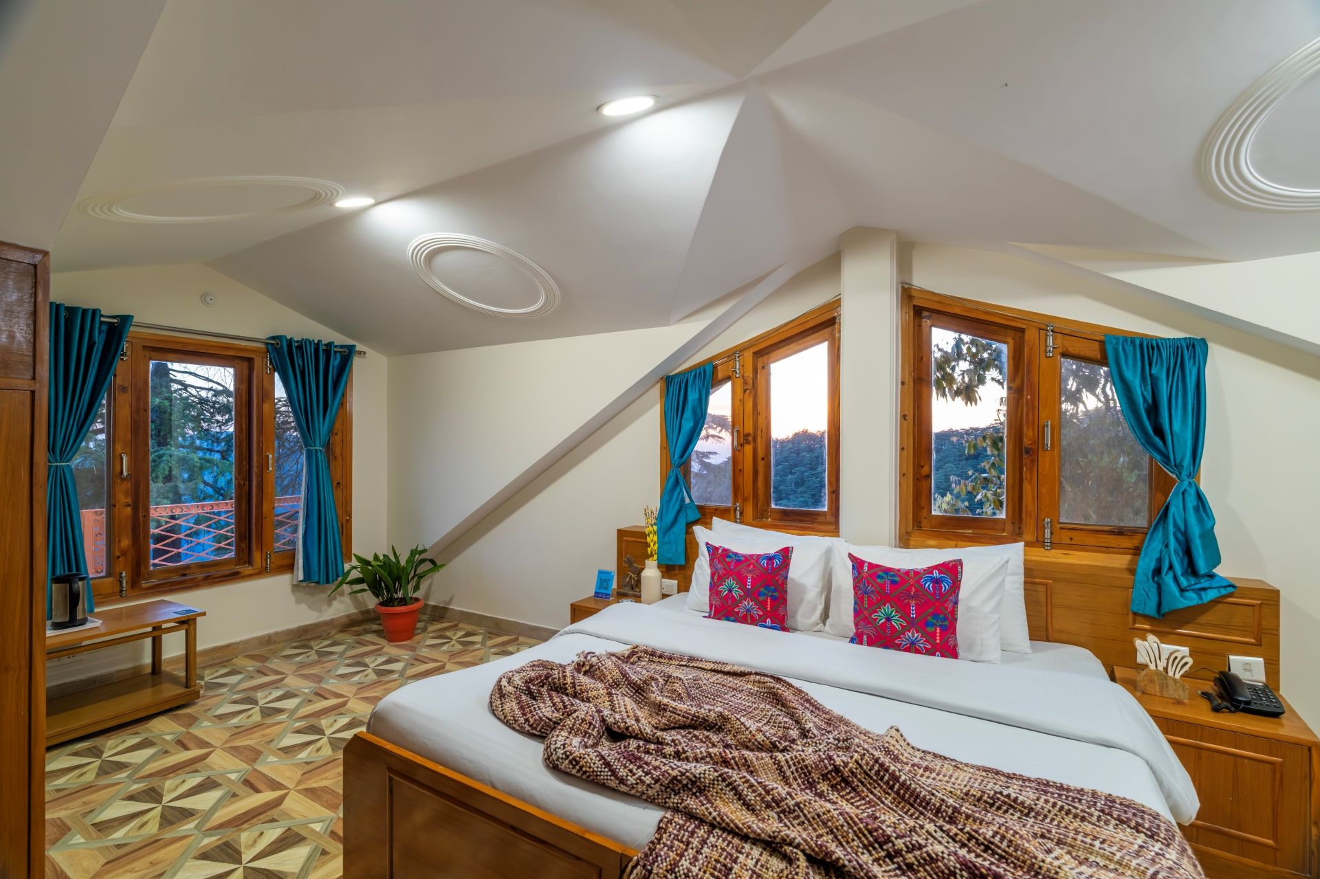 A bedroom with a bed, a potted plant, and a window with curtains.