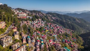 A hillside town with densely packed buildings, a prominent multi-story hotel, and a clear view of the surrounding mountains. - Kalra Regency Shimla (Shimla)