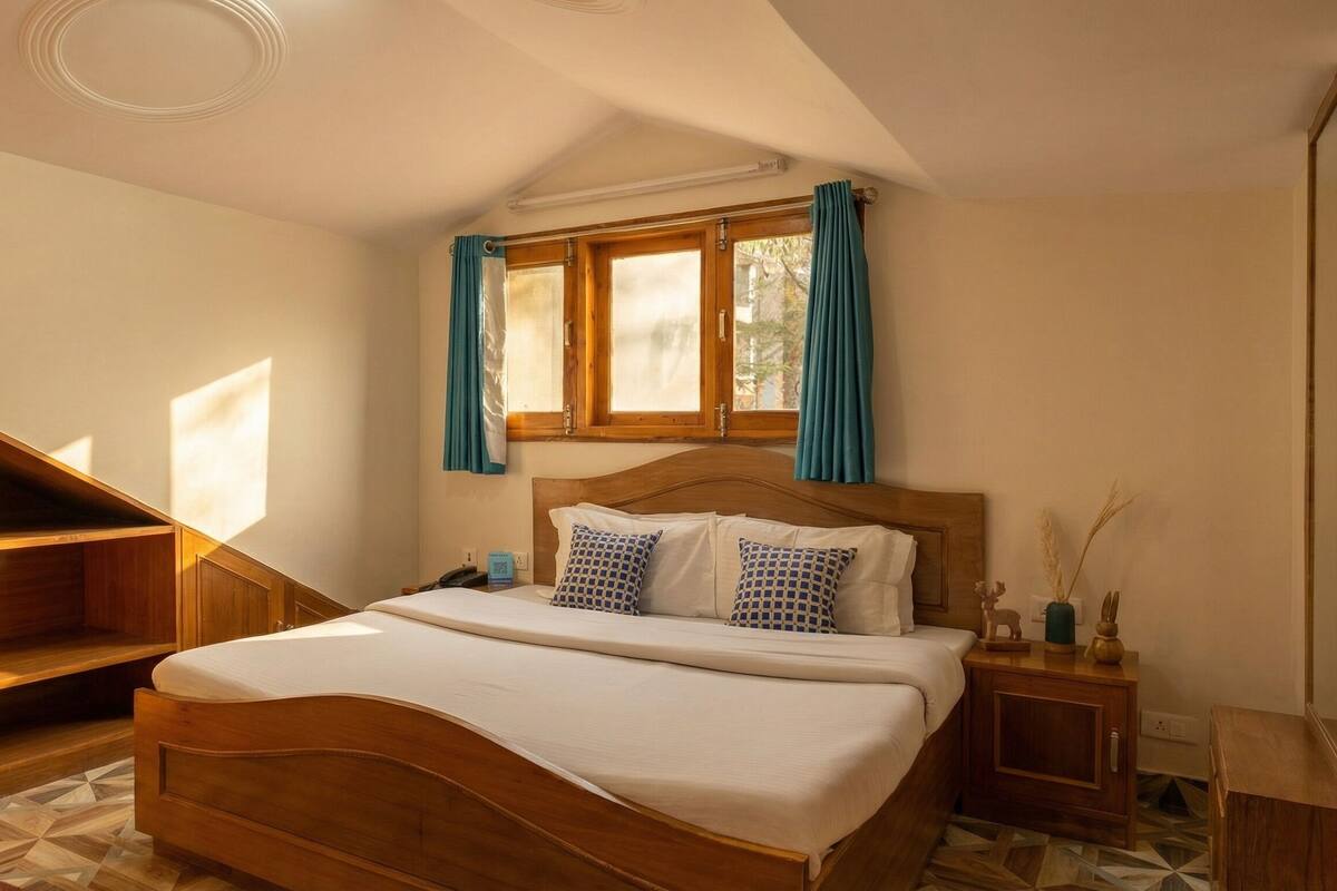 A bedroom with a wooden bed, a window with curtains, a nightstand, and a small table with a vase.