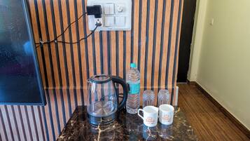 Una cocina con cafetera, hervidor, botella de agua y dos tazas sobre una encimera de mármol.