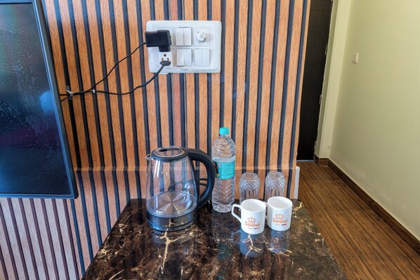 Un comptoir de cuisine avec une machine à café, une bouteille d’eau et deux tasses à café.