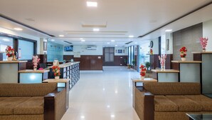 A hotel reception area with a central desk, seating on both sides, and a clear view of the lobby. - La Comfort By shrpl (Gurugram)
