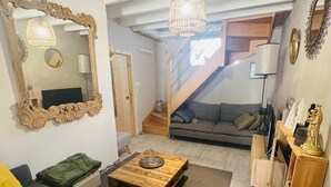 Uma sala de estar com um sofá, uma mesa de centro, um espelho, uma escada e um abajur.