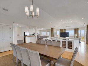 Un comedor amplio con una mesa larga y sillas, una cocina con armarios blancos y una isla grande con asientos.