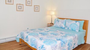 Un dormitorio con una cama, una mesita de noche, una lámpara y cuatro cuadros en la pared.