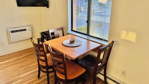 Un comedor con una mesa, sillas, un televisor montado en la pared y un aire acondicionado.
