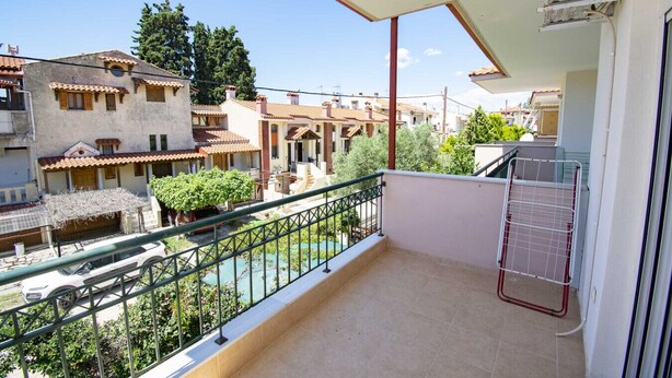 Ein Balkon mit Blick auf benachbarte Gebäude, einem Metallgeländer und einem gefliesten Boden.