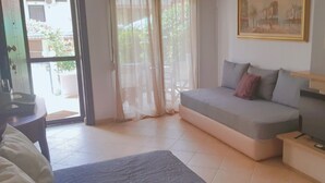 Ein Wohnzimmer mit einer Couch, einem Fernseher und einem Gemälde an der Wand.