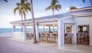 A beachside bar with outdoor seating, palm trees, and a view of the ocean. - Duval Street Stay + Free Breakfast, Pool & Bar (Key West)