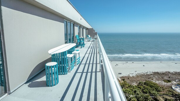Ein Balkon mit Sitzgelegenheit, Blick auf das Meer und den Strand.