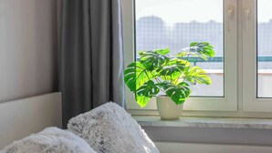 Ein Schlafzimmer mit einem Bett, einem Nachttisch, einem Fenster mit Blick und einer Topfpflanze.