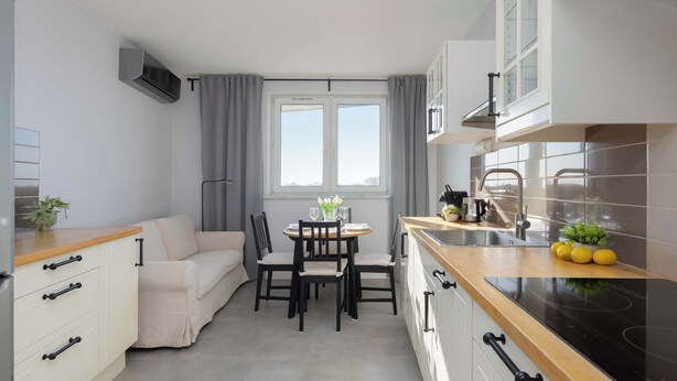 Eine kleine Küche mit Essbereich, einem Sofa und einem Fenster mit Vorhängen.
