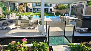 Ein überdachter Außenbereich mit Pool, Sitzgelegenheiten und Grill.