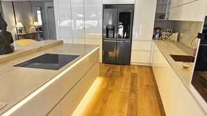 Eine moderne Küche mit Holzboden, weißen Schränken und eingebauten Geräten.
