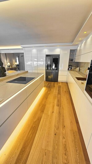 Eine moderne Küche mit Holzboden, weißen Schränken und einem eingebauten Backofen.