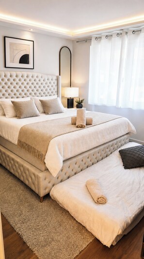 Ein Schlafzimmer mit einem großen Bett, einer zusätzlichen Schlafcouch, einem Nachttisch mit Lampe sowie einem gerahmten Bild an der Wand.