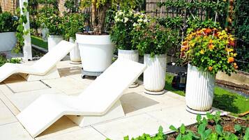 A garden with potted plants, a white structure, and a tiled patio area.