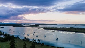A river with multiple boats, surrounded by greenery and distant hills. - River AND Salt - Spacious Family Escape Near Yamba's Best Beaches - Holiday Yamba (Yamba)