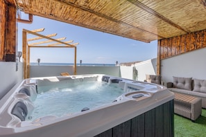 Een bubbelbad met een houten pergola, een bank en uitzicht op zee.