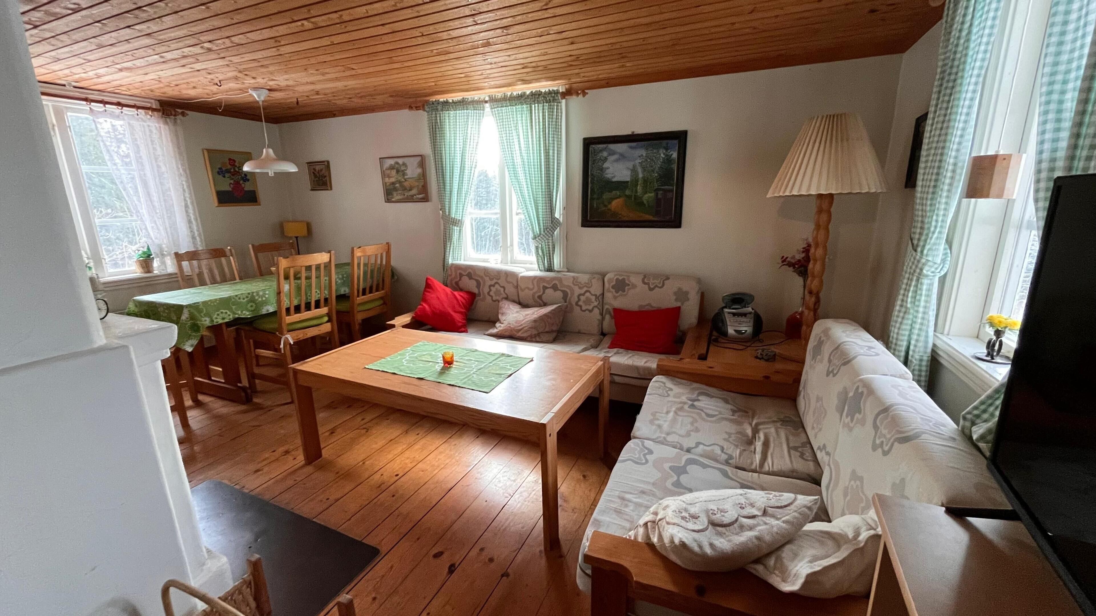 A cozy living room with a wooden table, sofa, and chairs.