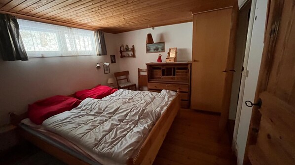A bedroom with a wooden bed, a dresser, a chair, a desk, and a wardrobe.