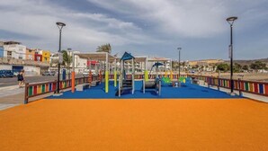 Ein Spielplatz mit buntem Spielgerät und einer blauen Spielfläche.