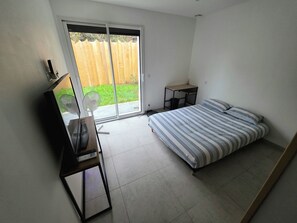 Una camera da letto con un letto, una scrivania, una sedia, un tavolino e una porta vetrata scorrevole che dà su un patio.