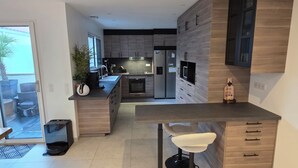 Una cocina moderna con una isla central, electrodomésticos integrados y una zona de estar.