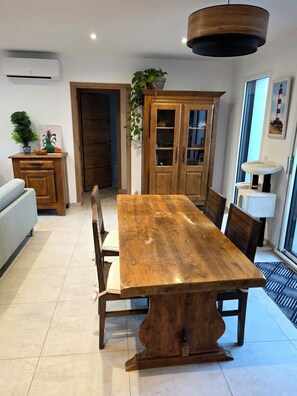 Zona pranzo con tavolo in legno, sedie, un armadietto e una lampada a sospensione.