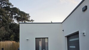 Un edificio moderno con techo plano, puerta de garaje y una puerta con panel de vidrio.