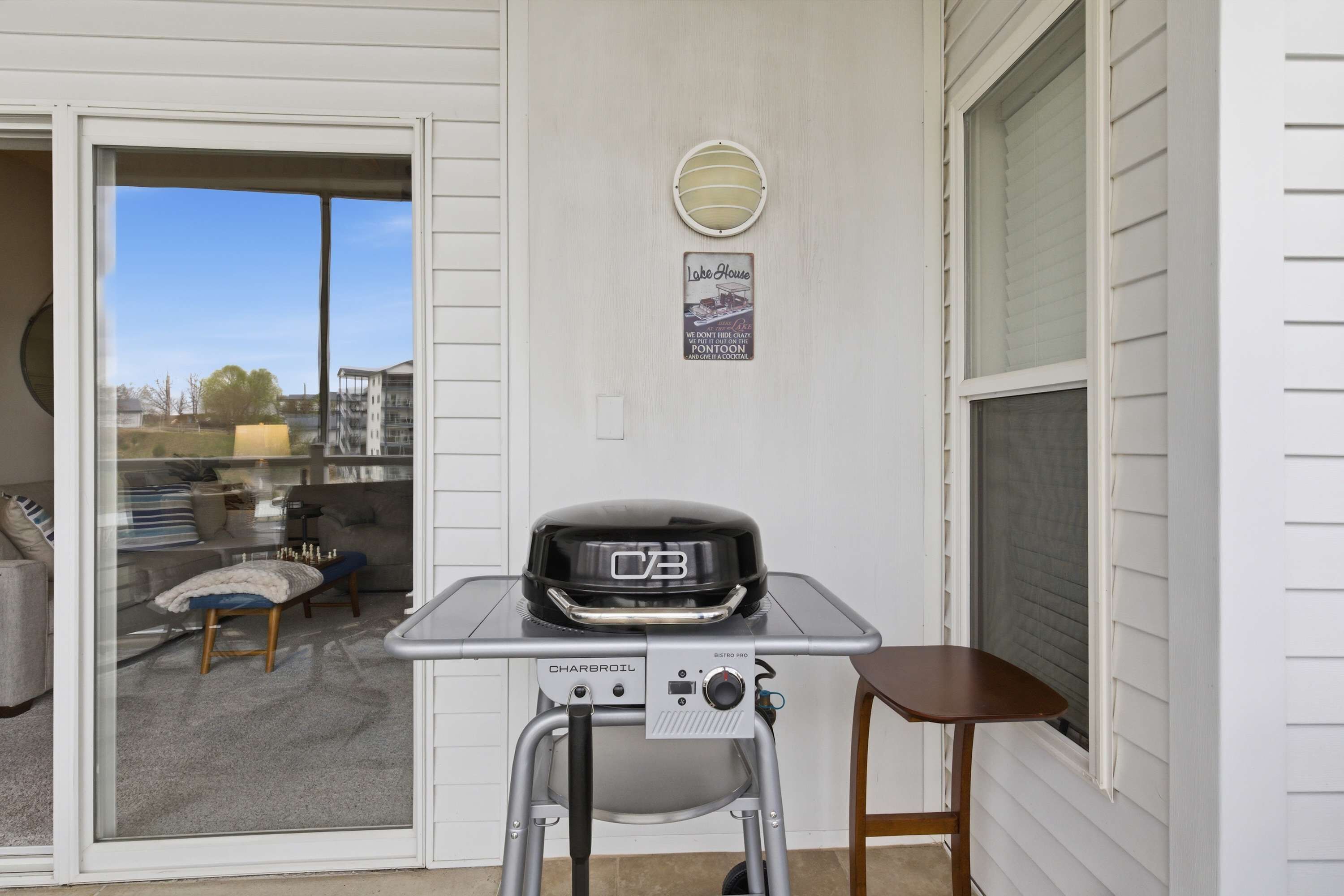 Een draagbare barbecue op een tafel voor een huis, met een schuifdeur naar een terras.