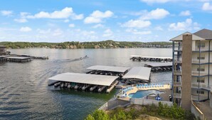 A waterfront hotel with multiple docked boats, a pool area, and a building with balconies. - 2B 2B | Lake View | Seasonal Pool | Hot Tub |Grill (Lake Ozark)