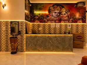 A reception desk with a check-in counter, a decorative vase, and a wall mural. - Sivago hotel (Chhata)