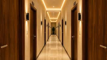 A hotel corridor with wooden doors, numbered room signs, and a polished marble floor.