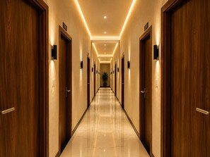 A hotel corridor with wooden doors, numbered room signs, and a polished marble floor. - Sivago hotel (Chhata)
