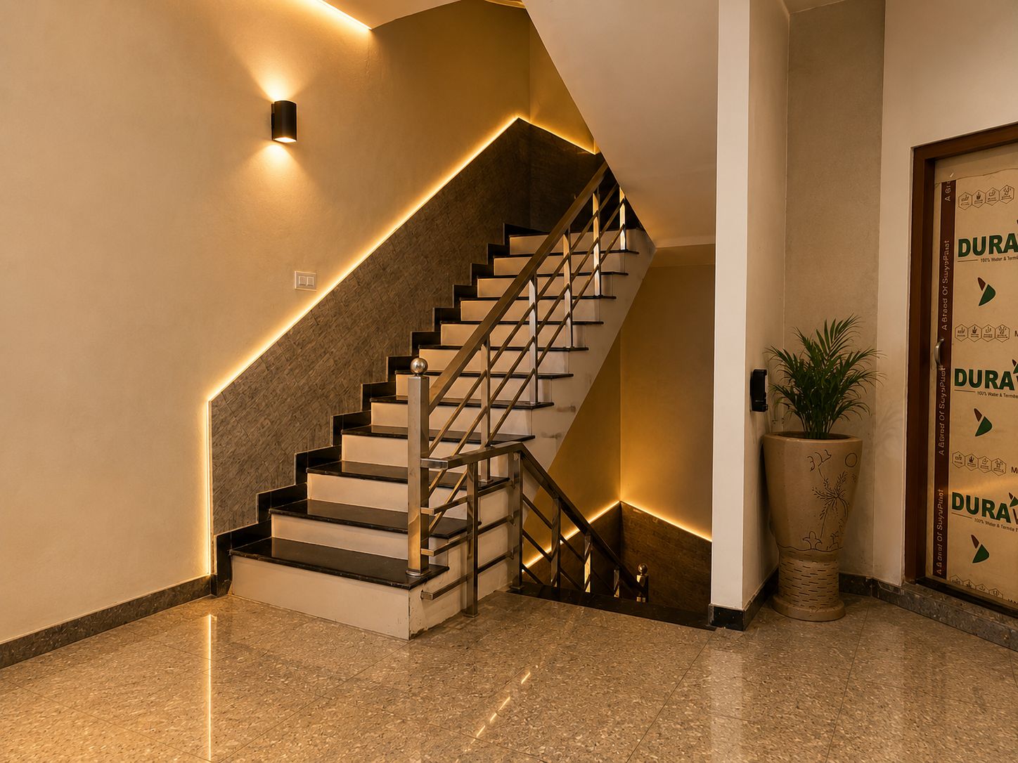 A modern staircase with a glass railing and a potted plant beside it.