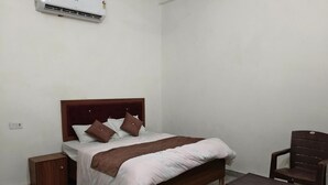 Een slaapkamer met een bed, nachtkastjes, een stoel en een airconditioning.