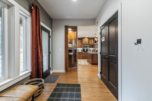 A hallway leading to a kitchen with wooden cabinets, a bench, and a rug.