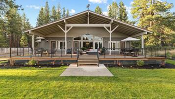 A covered outdoor seating area with a bench, tables, and chairs.