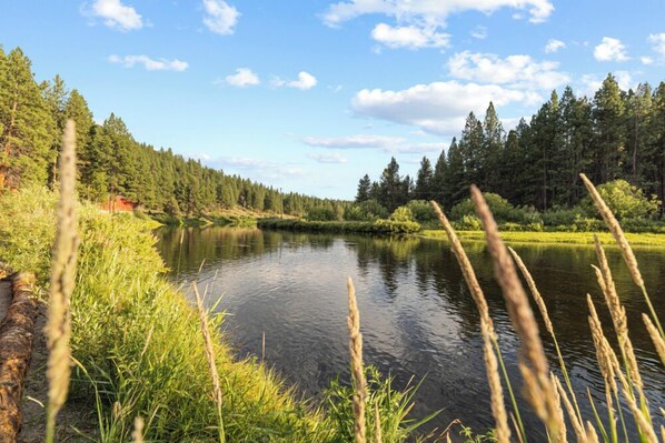 A serene lake surrounded by dense forest and a clear sky. - Chiloquin Ridge River Retreat | Riverfront • Near Crater Lake • Kayaks • Fireplace (Chiloquin)