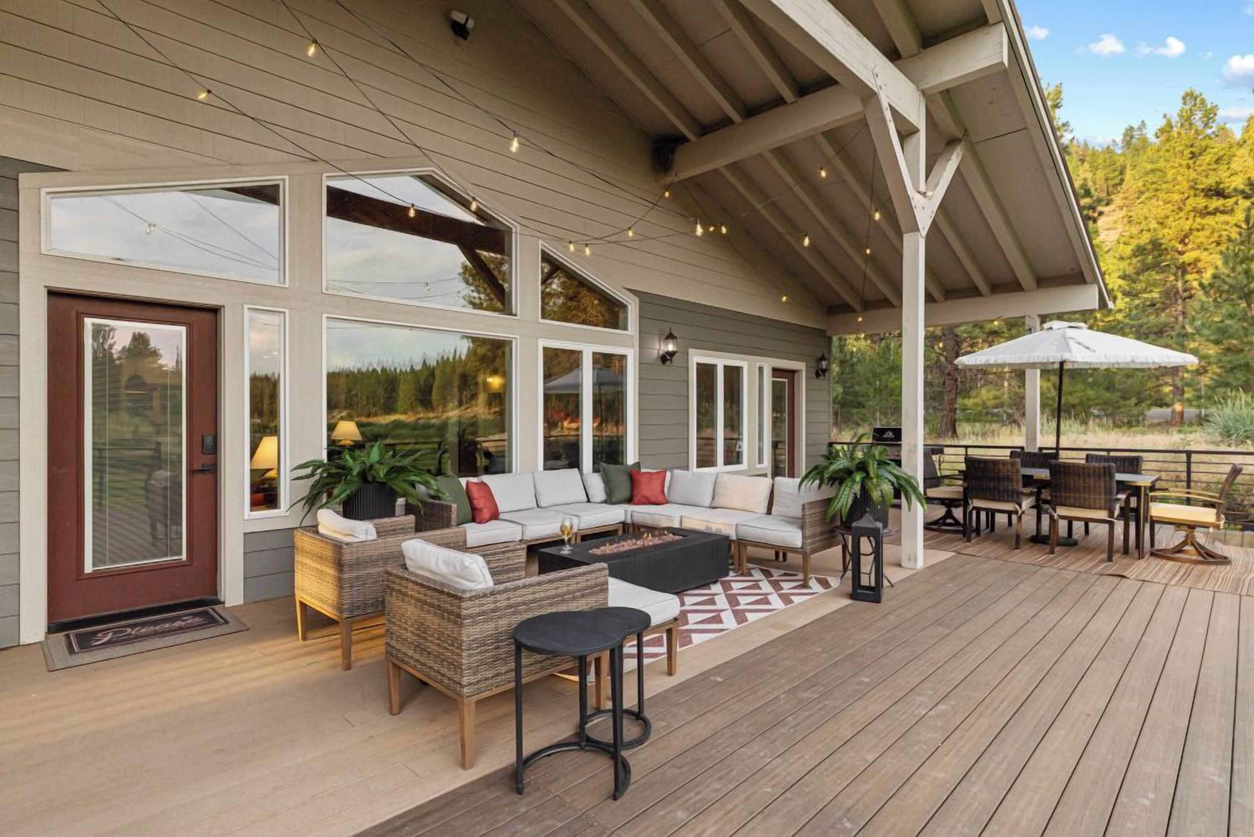 Une terrasse extérieure couverte, aménagée avec un canapé, des fauteuils et un coin repas.