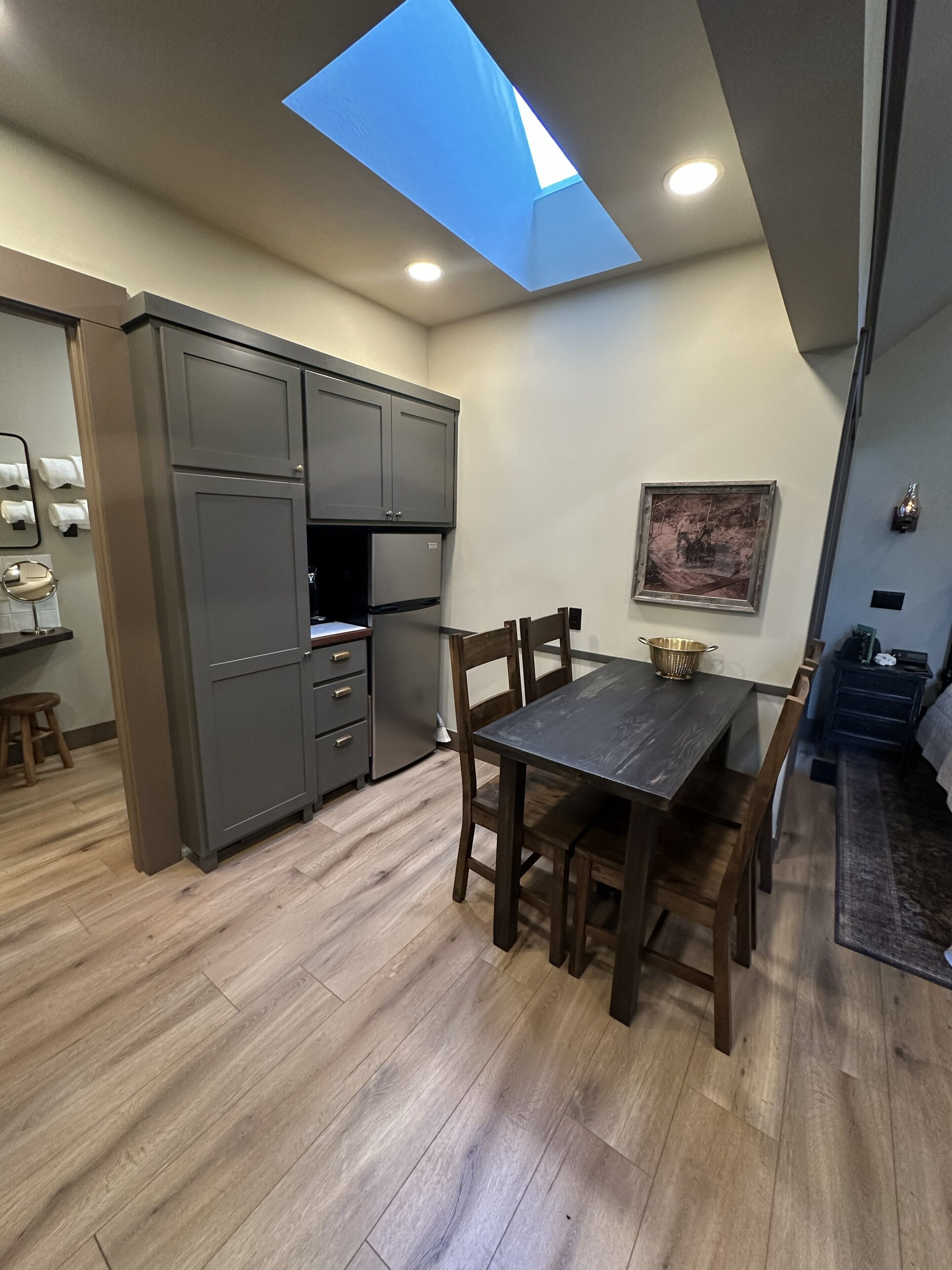 Una cocina compacta con tragaluz, suelo de madera y zona de comedor con sillas.