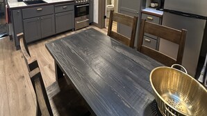 Eine moderne Küche mit grauen Schränken, einem Holzesstisch und einem Oberlicht.