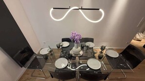 Un comedor moderno con una mesa de vidrio, sillas negras y una lámpara de techo original.