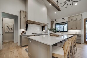 A modern kitchen with a large island, wooden cabinets, and a pendant light. - Spacious Lake Escape! Lakefront w/ Dock + Kayaks~Sleeps 10~2 Living Areas (Hot Springs)